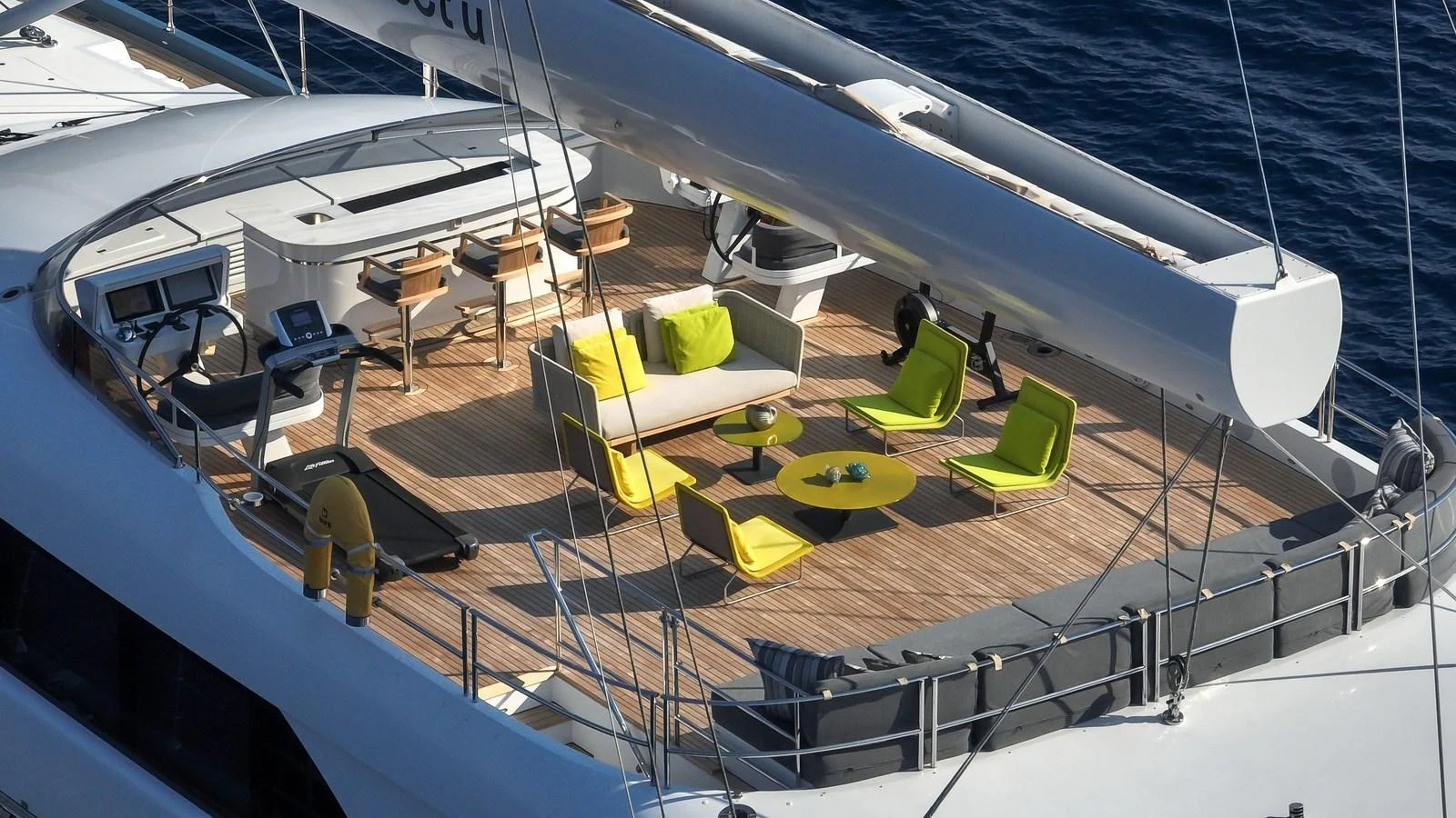 The sundeck features a stylish seating area with vibrant green cushions and a bar, perfect for relaxation and socializing. aboard ALL ABOUT U Yacht for Sale