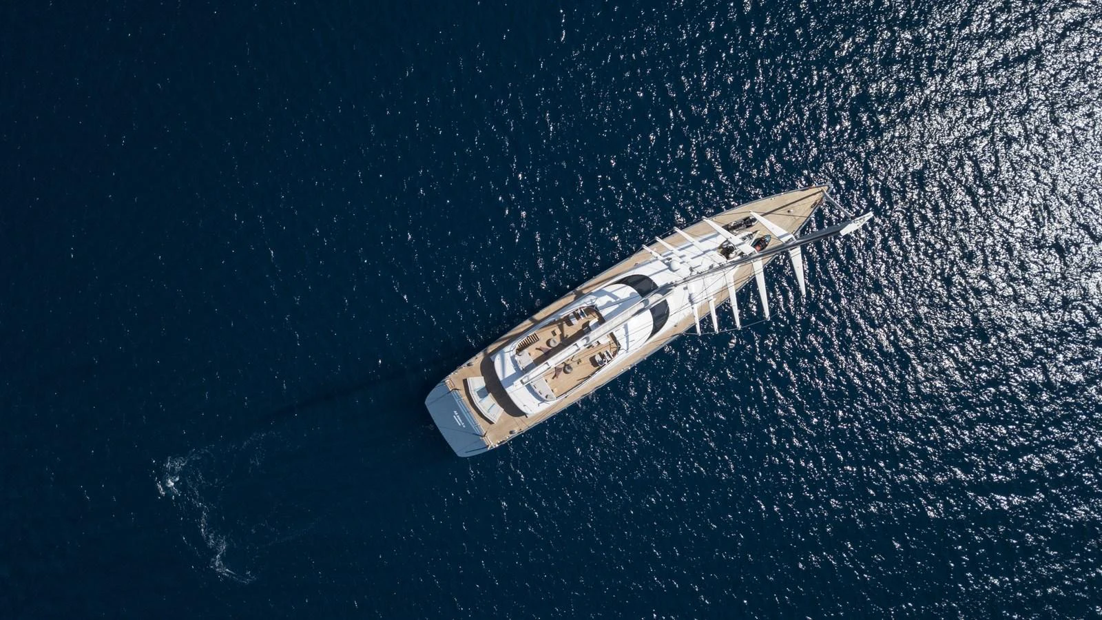 An elegant yacht glides through the deep blue sea, captured from an aerial perspective. aboard ALL ABOUT U Yacht for Sale