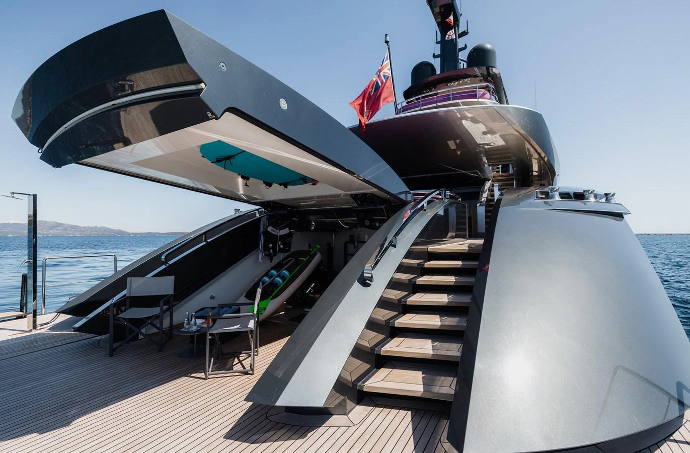 The yacht's aft deck features a sleek design with open compartments revealing water toys and a modern staircase leading to the upper deck. aboard FLYING DAGGER III Yacht for Sale