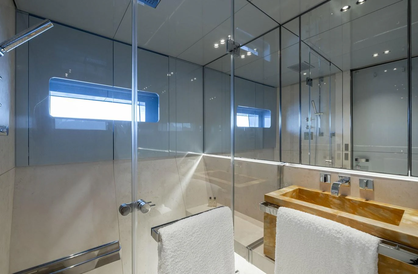 The yacht's bathroom features sleek modern design with glass walls and a wooden sink. aboard FLYING DAGGER III Yacht for Sale