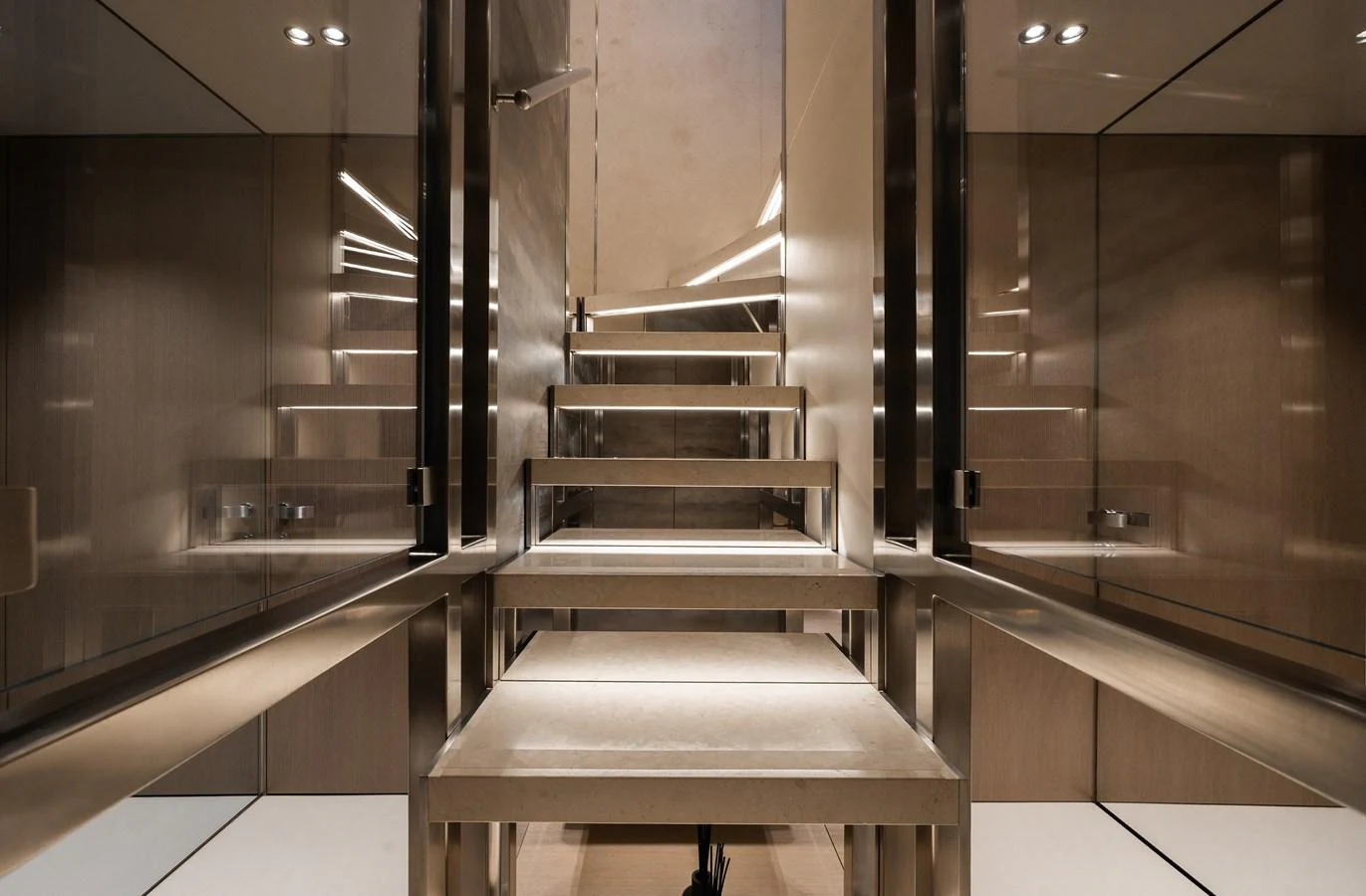 A modern and sleek staircase with reflective surfaces and ambient lighting. aboard FLYING DAGGER III Yacht for Sale