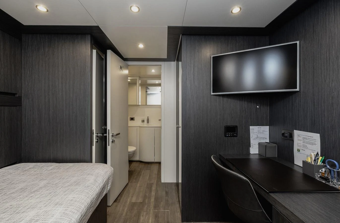 A modern crew cabin featuring a bed, desk, and ensuite bathroom. aboard FLYING DAGGER III Yacht for Sale