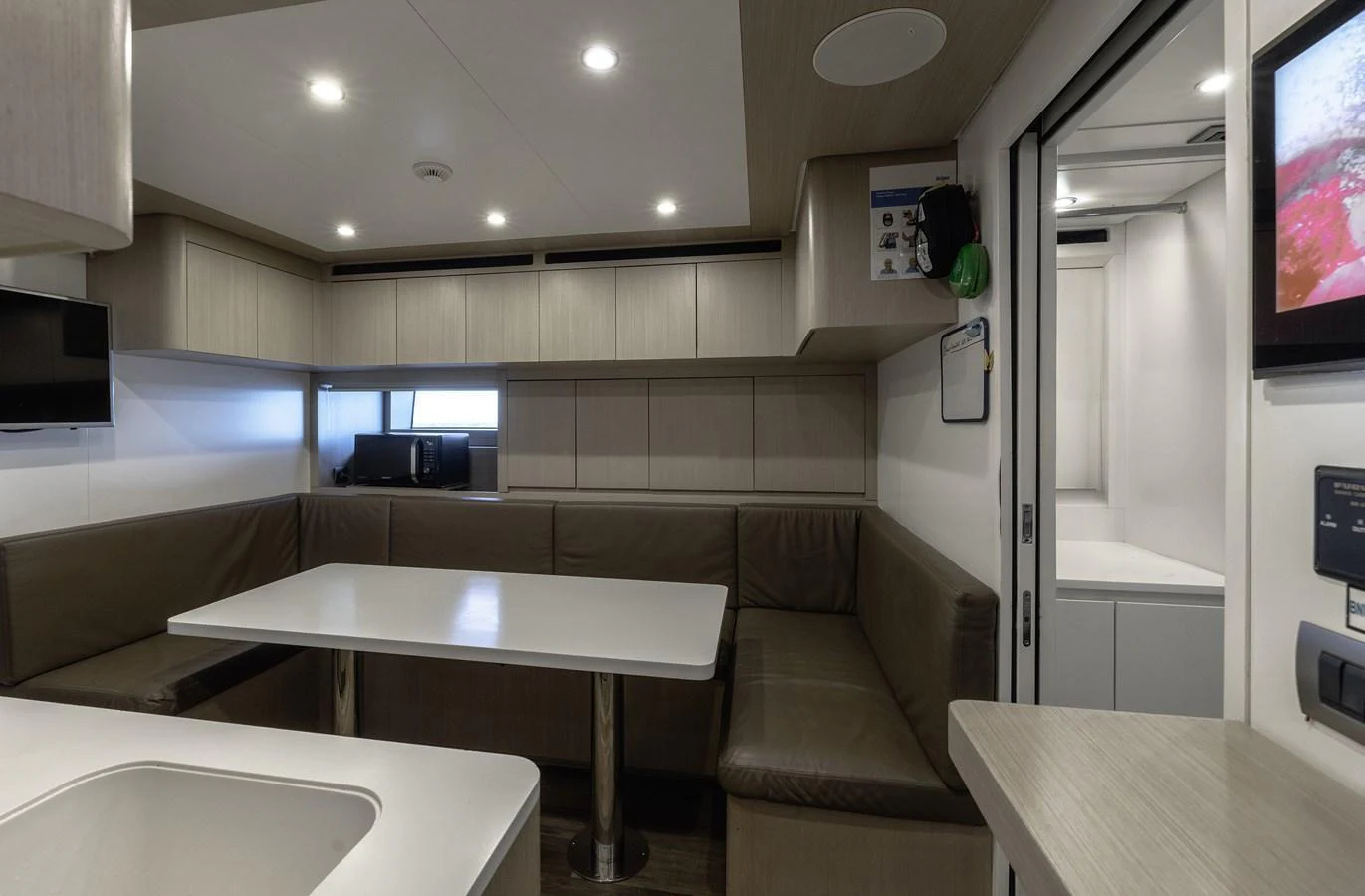 The yacht's dining area features a cozy seating arrangement with a sleek table and modern lighting. aboard FLYING DAGGER III Yacht for Sale