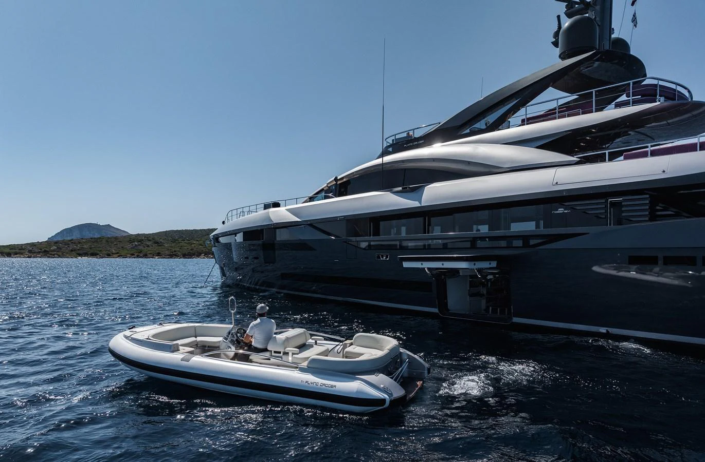 A sleek tender is seen floating beside a luxurious yacht on a calm, sunny day. aboard FLYING DAGGER III Yacht for Sale