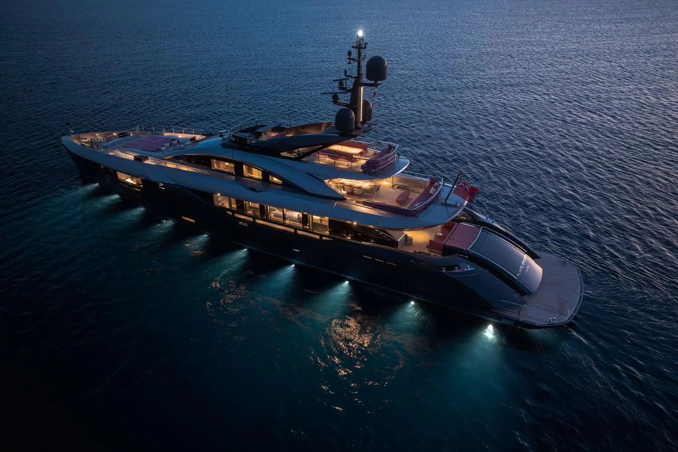 A sleek and modern yacht is illuminated against the tranquil evening sea. aboard FLYING DAGGER III Yacht for Sale