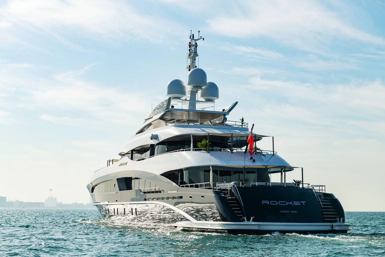 A luxurious yacht cruises gracefully on the open water under a clear sky. aboard ROCKET Yacht for Sale