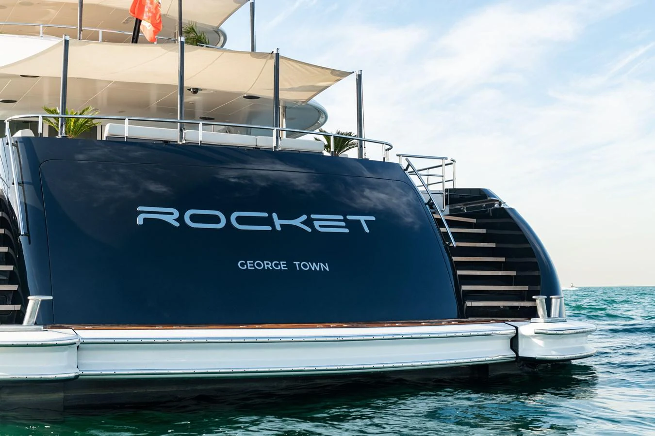 The stern of the yacht showcases a sleek design with elegant stairs leading to the deck. aboard ROCKET Yacht for Sale