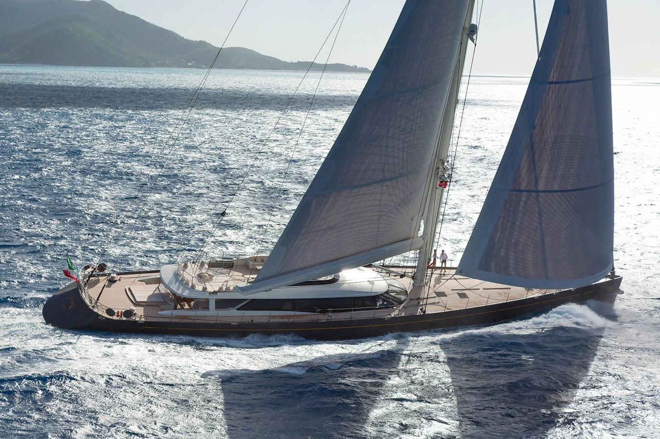 A sleek sailing yacht glides gracefully over the water, showcasing its elegant design and expansive deck. aboard OHANA Yacht for Sale