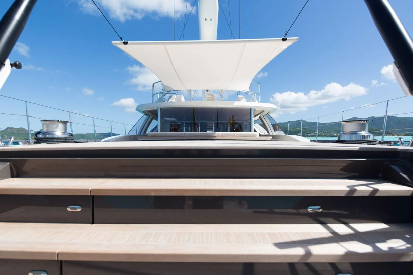 The yacht's aft deck features elegant steps leading up to a shaded area with stunning views. aboard OHANA Yacht for Sale