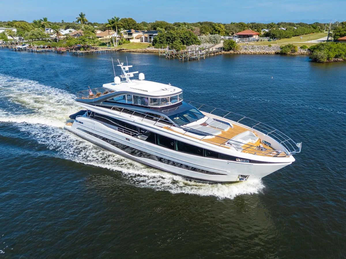A sleek and modern yacht cruising through calm waters with a scenic shoreline in the background. aboard JUST PERFECT Yacht for Sale