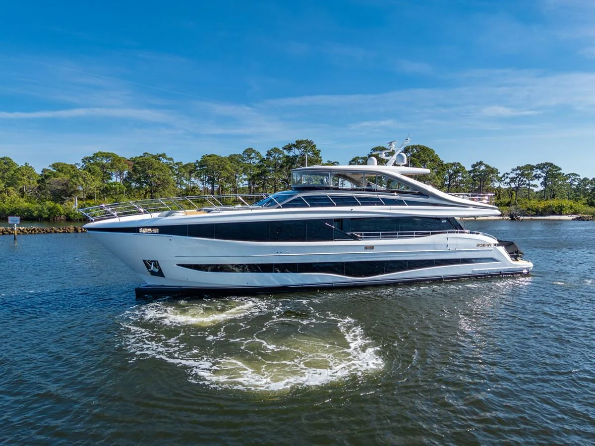 A sleek and modern yacht glides gracefully on calm waters against a backdrop of lush greenery. aboard JUST PERFECT Yacht for Sale
