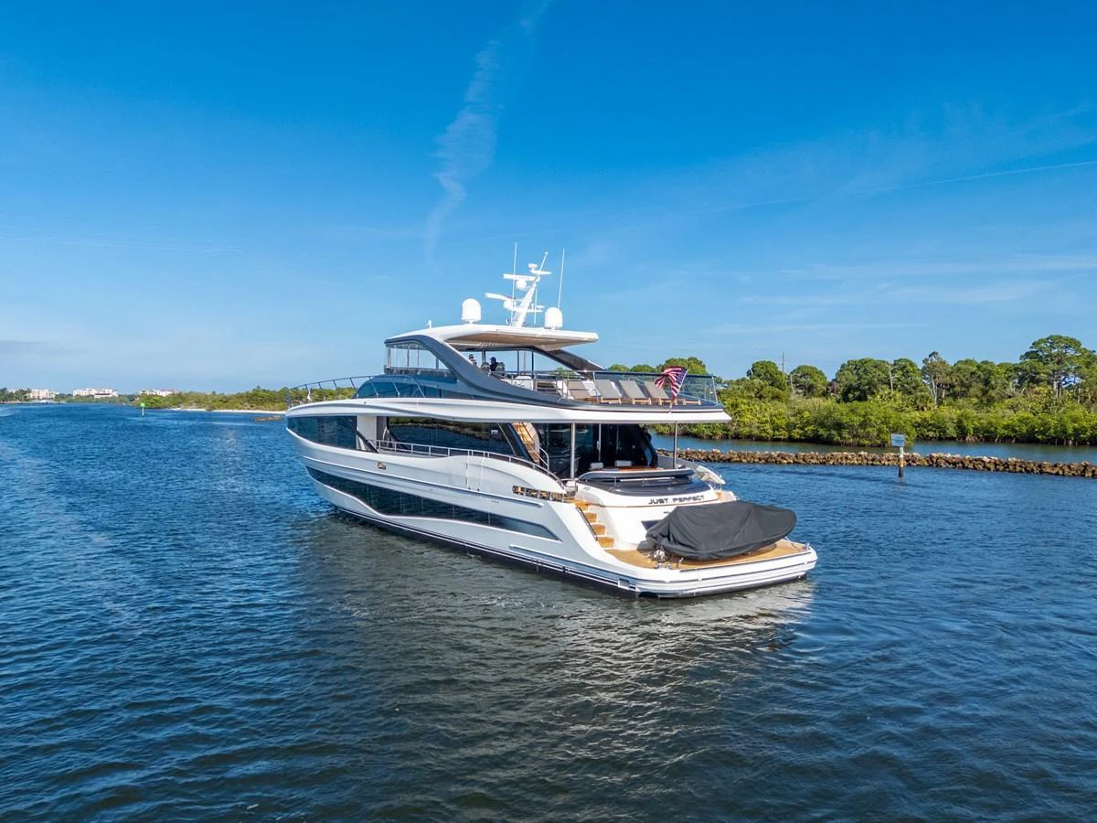 A sleek and modern yacht cruising on calm waters under a clear blue sky. aboard JUST PERFECT Yacht for Sale