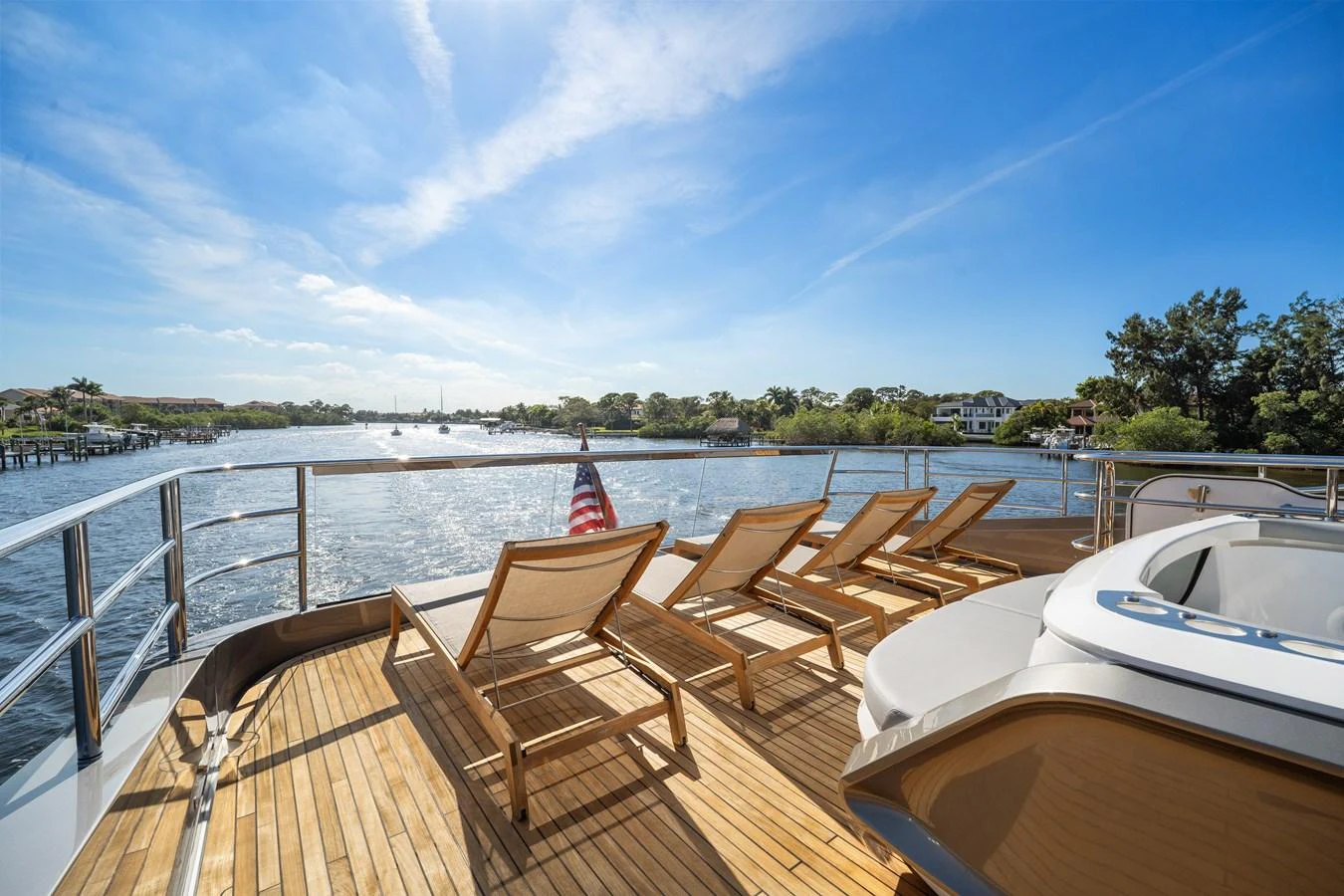 The sundeck offers a serene space with lounge chairs and a jacuzzi, perfect for relaxation under the blue sky. aboard JUST PERFECT Yacht for Sale