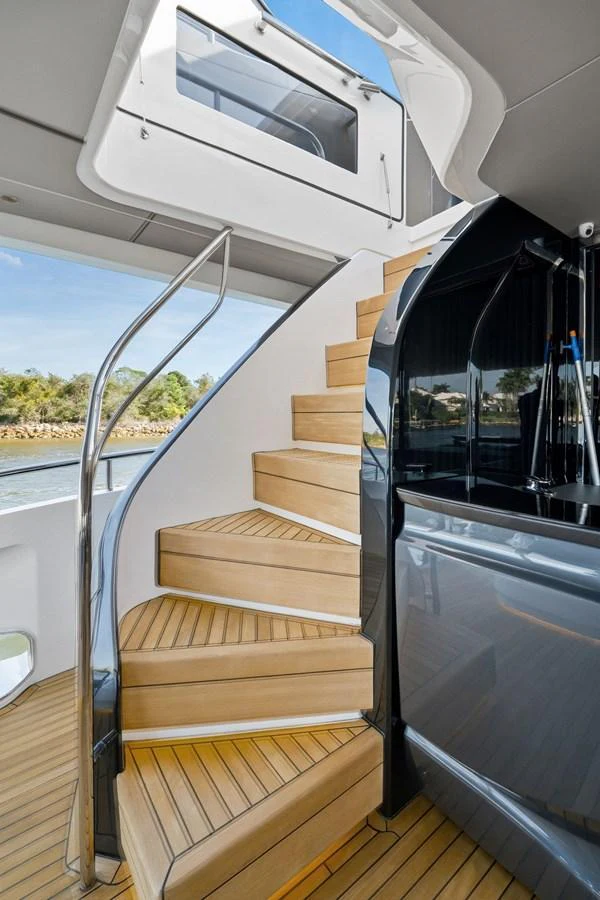 A sleek, modern staircase with wooden steps and a polished metal railing leads to the upper deck. aboard JUST PERFECT Yacht for Sale