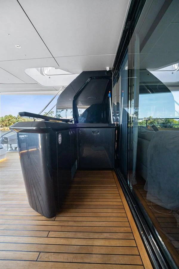 A sleek outdoor bar area with a glossy black finish and wooden decking. aboard JUST PERFECT Yacht for Sale