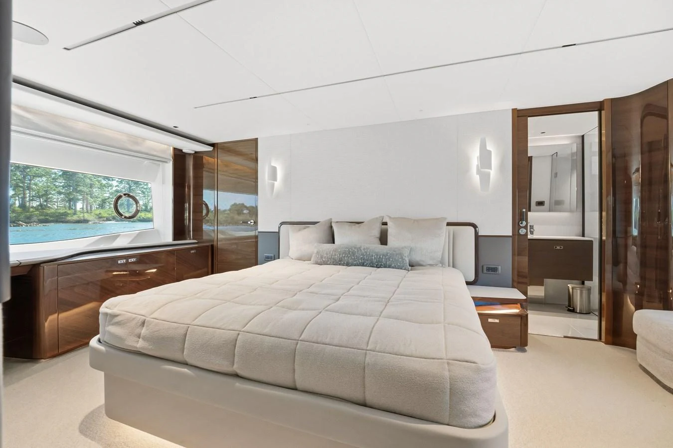 The stateroom features a plush bed with elegant wood accents and a serene view through the window. aboard JUST PERFECT Yacht for Sale