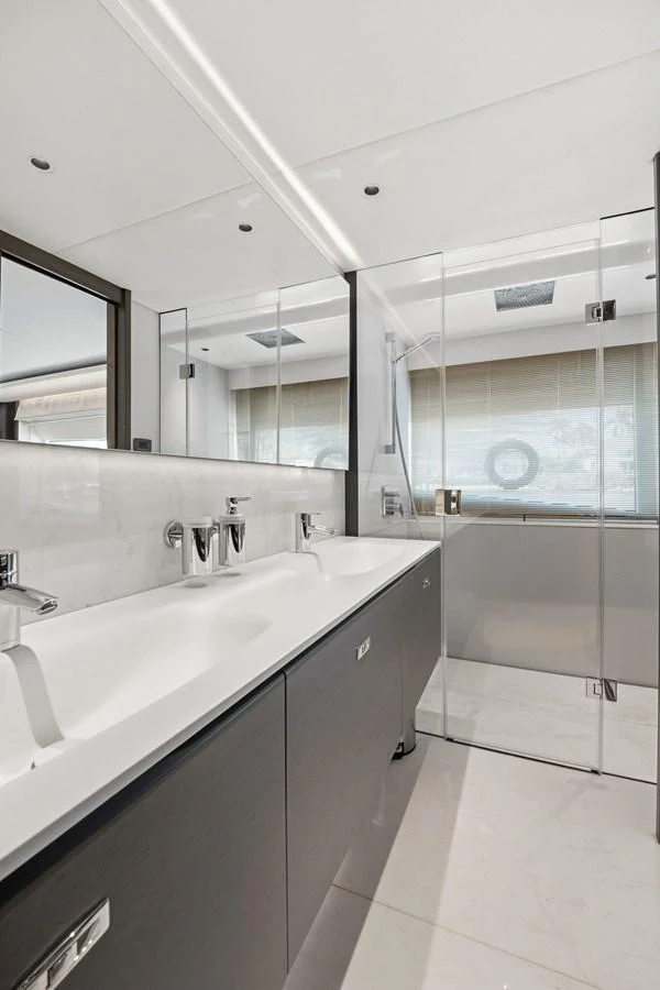 The yacht's bathroom features a sleek, modern design with dual sinks and a glass-enclosed shower. aboard JUST PERFECT Yacht for Sale