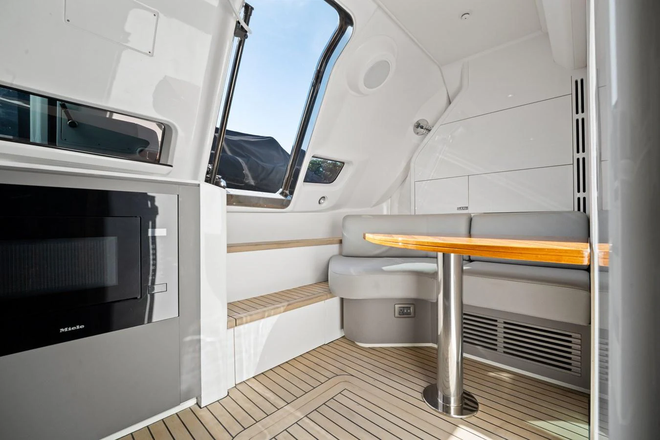 The yacht's saloon features a cozy seating area with a wooden table and large windows for natural light. aboard JUST PERFECT Yacht for Sale
