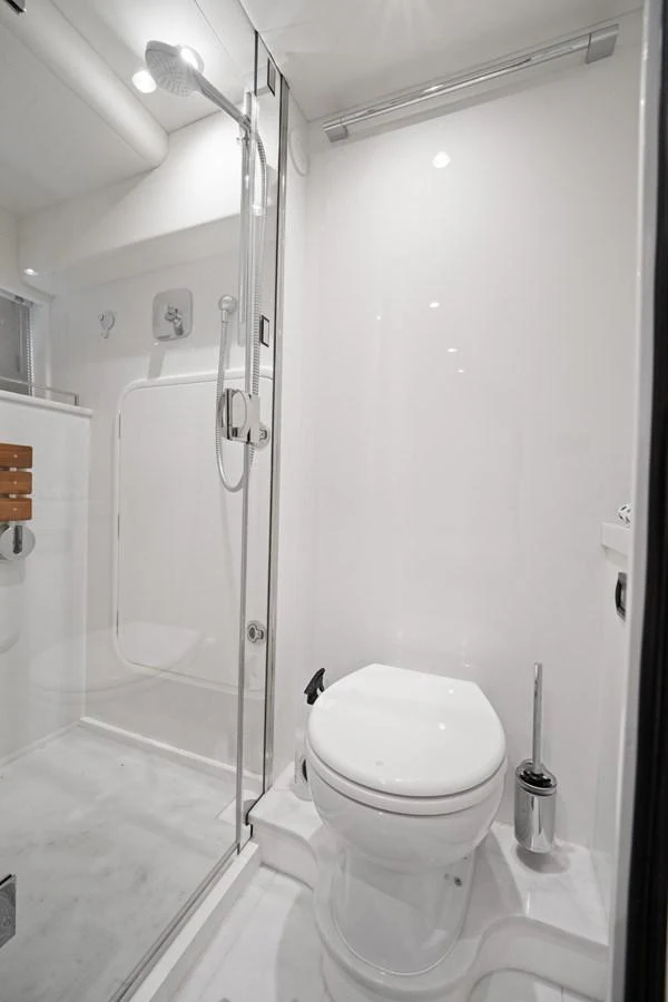 The yacht's bathroom features a sleek, modern design with a glass-enclosed shower and pristine white fixtures. aboard JUST PERFECT Yacht for Sale