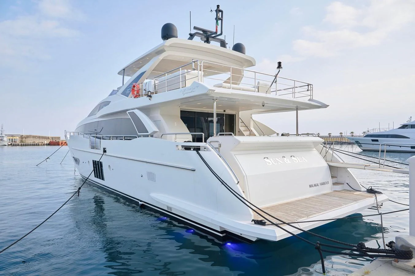 A sleek and modern yacht is docked at the marina, showcasing its spacious aft deck and elegant design. aboard SUN & SEA Yacht for Sale