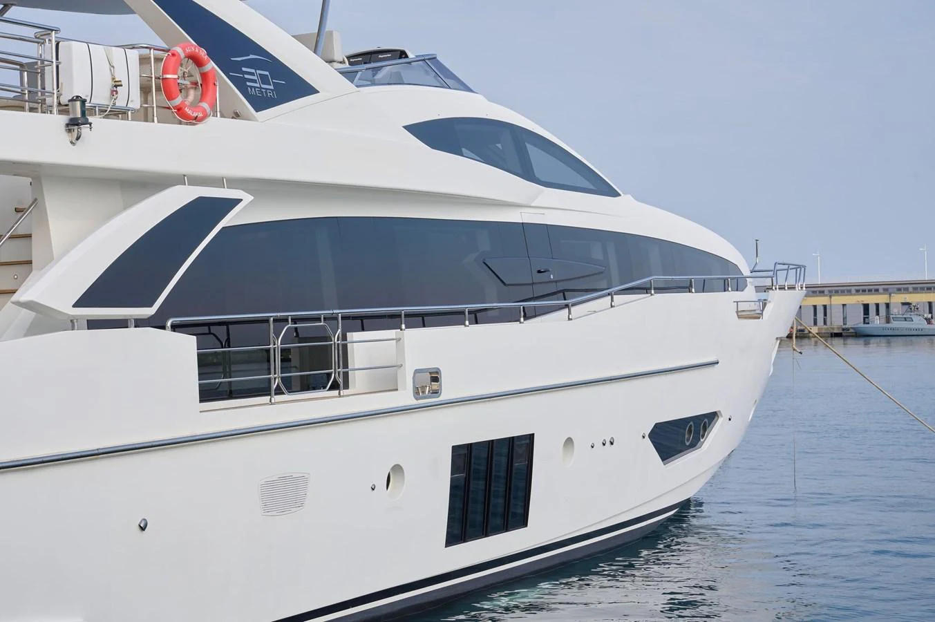 A sleek and modern yacht is docked in calm waters, showcasing its elegant design and expansive windows. aboard SUN & SEA Yacht for Sale