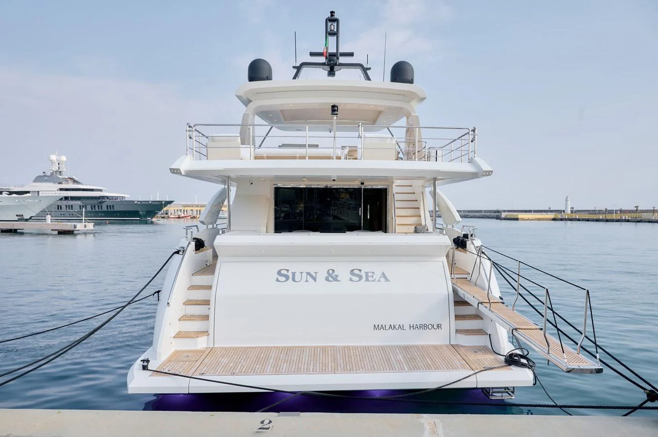 A luxurious yacht docked at the harbor, showcasing its spacious aft deck and elegant design. aboard SUN & SEA Yacht for Sale