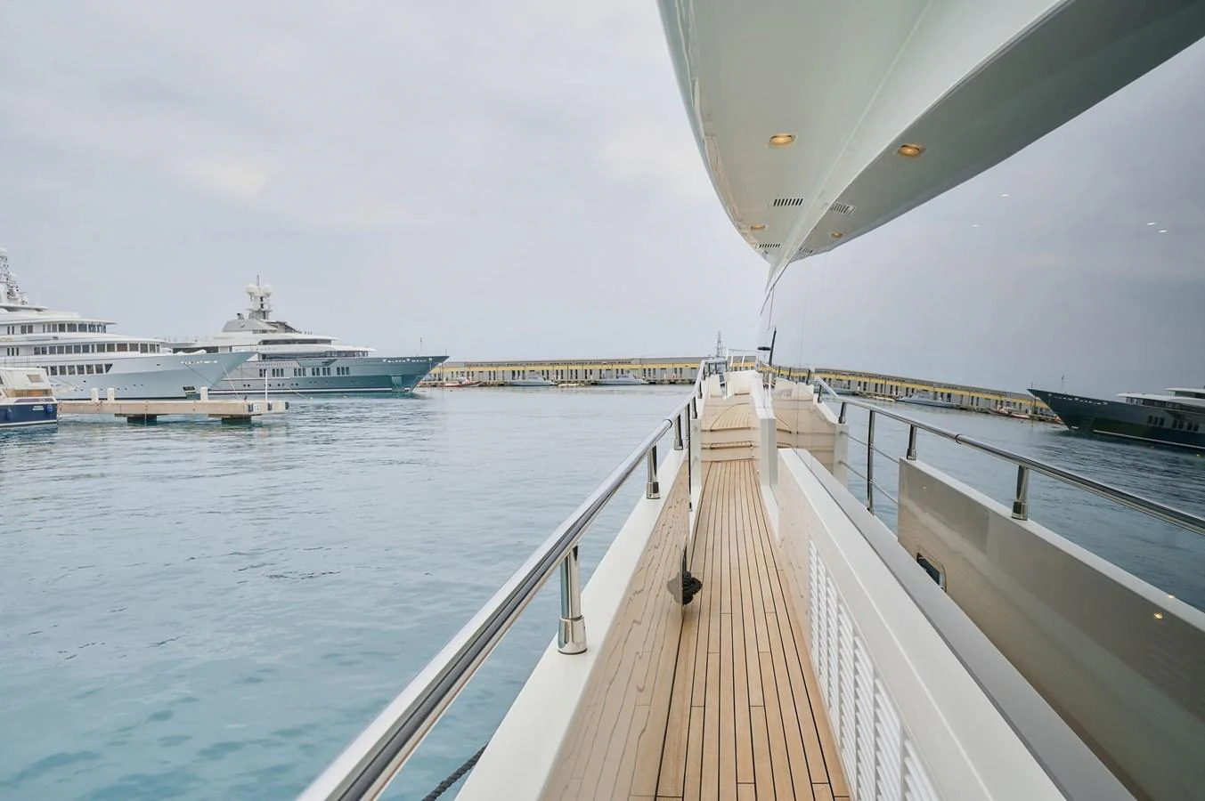 The side deck of the yacht offers a spacious walkway with sleek railings and a view of the serene marina. aboard SUN & SEA Yacht for Sale