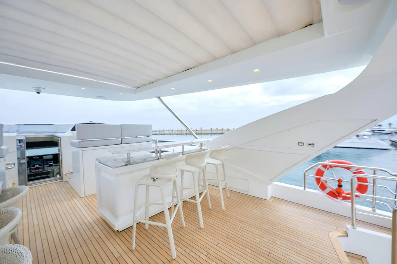 The flybridge features a sleek bar area with modern seating and a view of the marina. aboard SUN & SEA Yacht for Sale