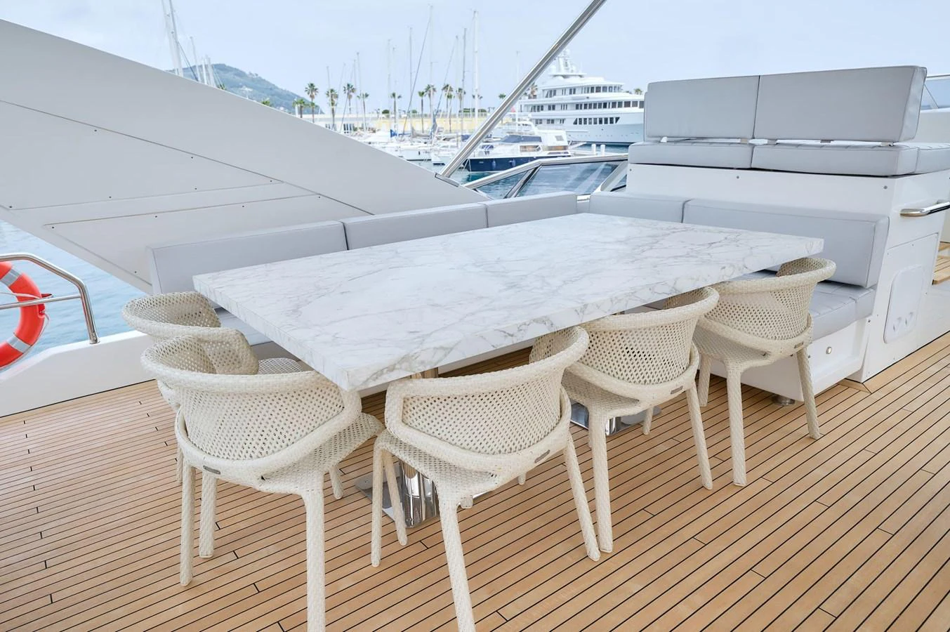 The yacht features a stylish outdoor dining area with a marble table and comfortable seating. aboard SUN & SEA Yacht for Sale