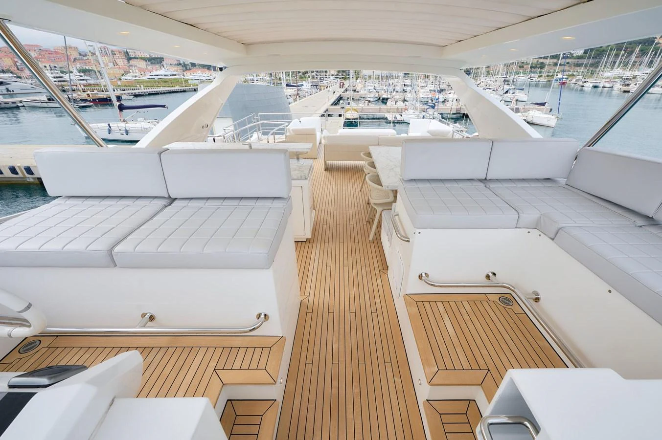 The flybridge offers ample seating with plush cushions and a stunning view of the marina. aboard SUN & SEA Yacht for Sale