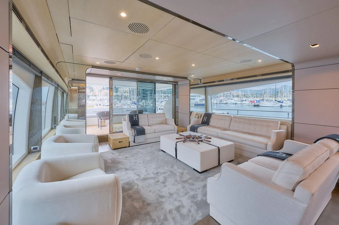 The spacious salon features plush seating and large windows offering stunning marina views. aboard SUN & SEA Yacht for Sale