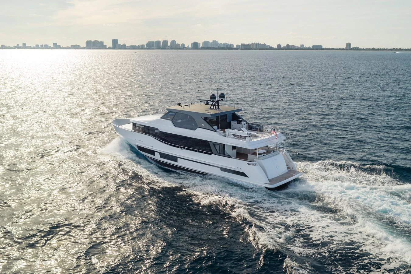 A sleek and modern yacht cruises through open waters with a cityscape in the background. aboard OCEAN ALEXANDER 28L Yacht for Sale