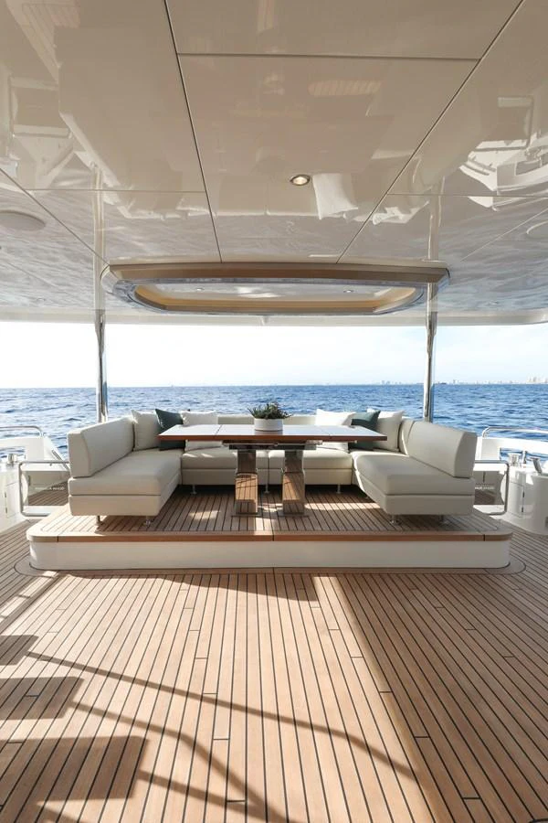 The aft deck features a spacious seating area with a wooden table, perfect for outdoor dining with a view of the sea. aboard OCEAN ALEXANDER 28L Yacht for Sale