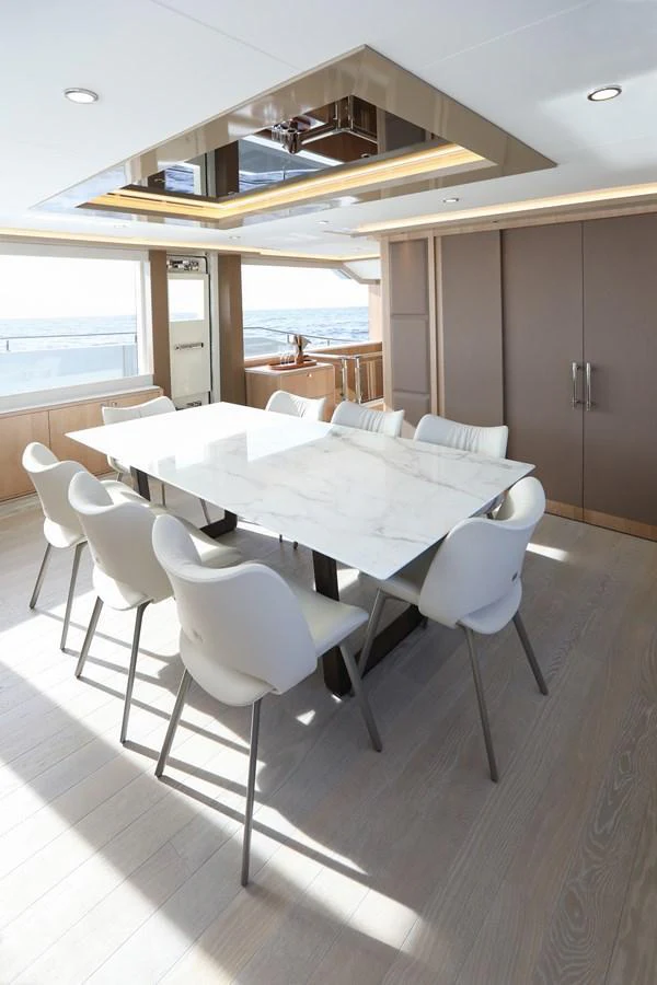 The yacht's dining area features a sleek marble table surrounded by modern white chairs, bathed in natural light. aboard OCEAN ALEXANDER 28L Yacht for Sale