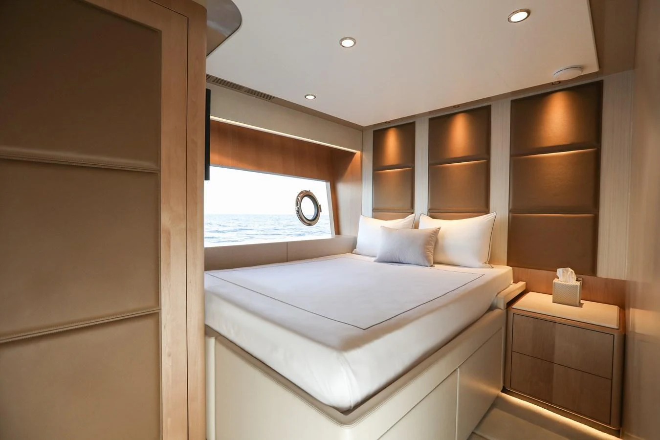 A luxurious stateroom featuring a large bed, modern lighting, and a view of the sea through a porthole. aboard OCEAN ALEXANDER 28L Yacht for Sale
