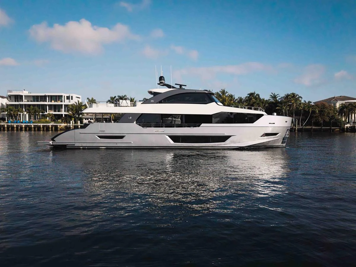 A sleek and modern yacht is gracefully cruising on calm waters with a luxurious waterfront backdrop. aboard CHAOS Yacht for Sale