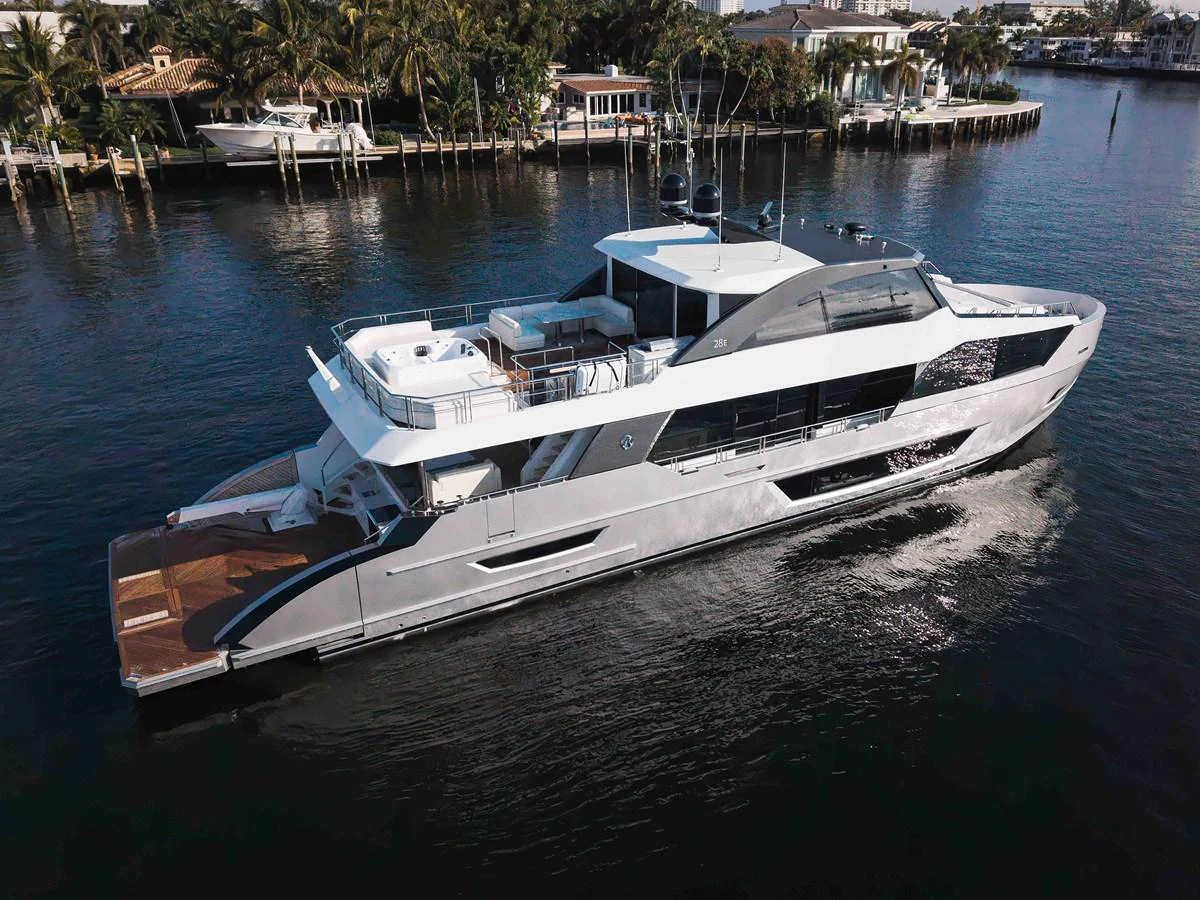 A sleek and modern yacht cruising along a serene waterfront with lush greenery in the background. aboard CHAOS Yacht for Sale