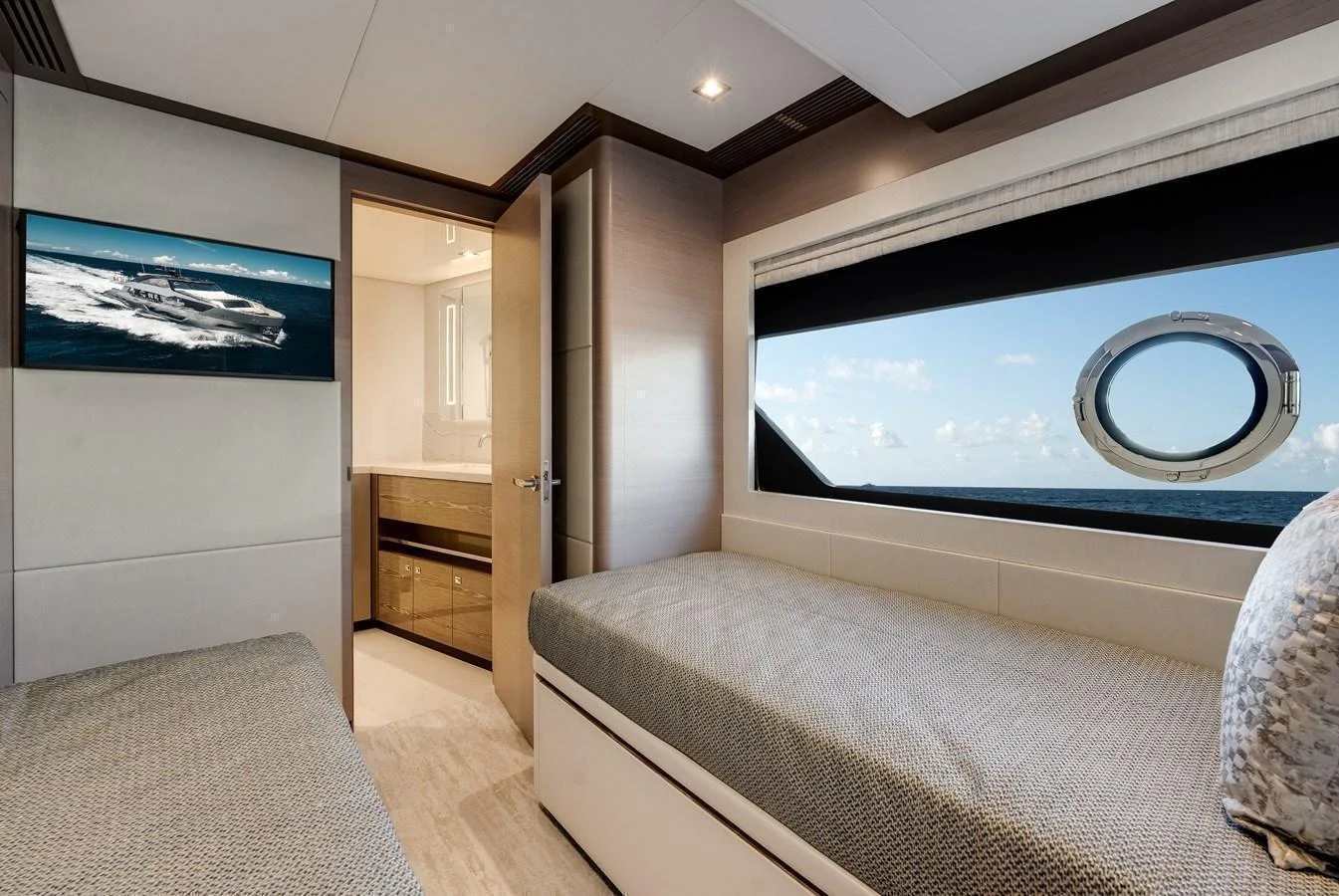 The guest stateroom features twin beds, a large window with an ocean view, and an ensuite bathroom. aboard CHAOS Yacht for Sale