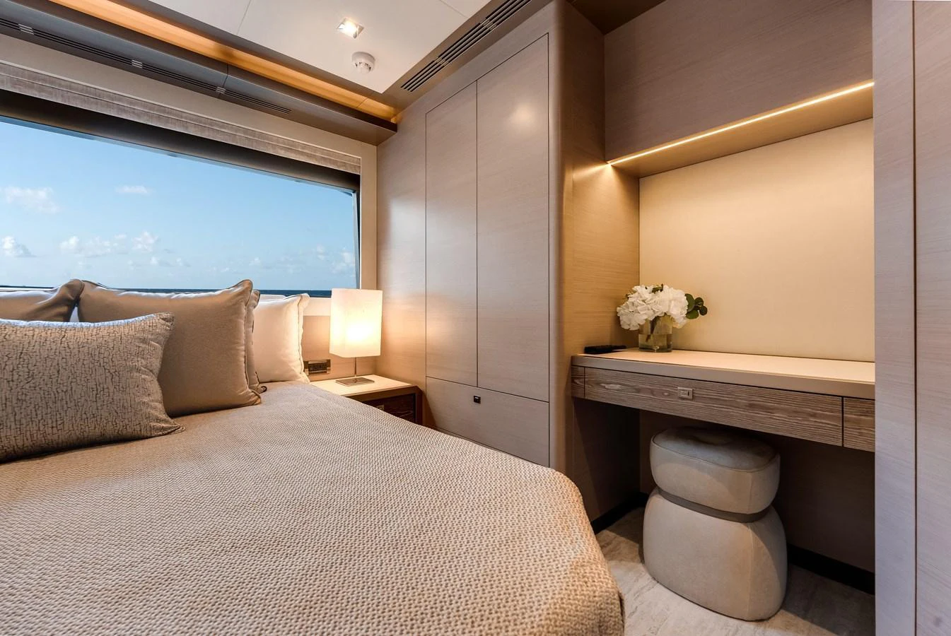 The stateroom features a comfortable bed, a desk area, and a large window with a scenic view. aboard CHAOS Yacht for Sale