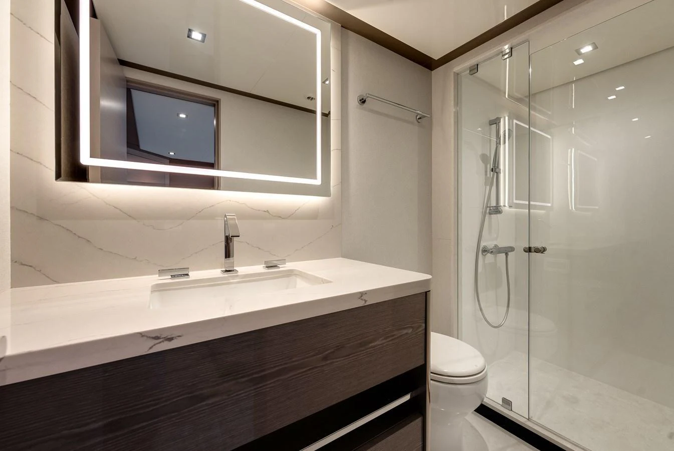 The yacht's bathroom features a sleek design with a modern vanity and a spacious glass-enclosed shower. aboard CHAOS Yacht for Sale