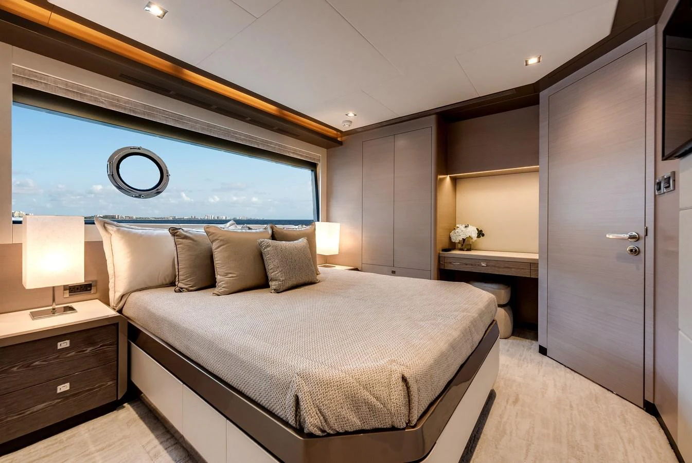 The master stateroom features a luxurious bed with a scenic view through a large window. aboard CHAOS Yacht for Sale