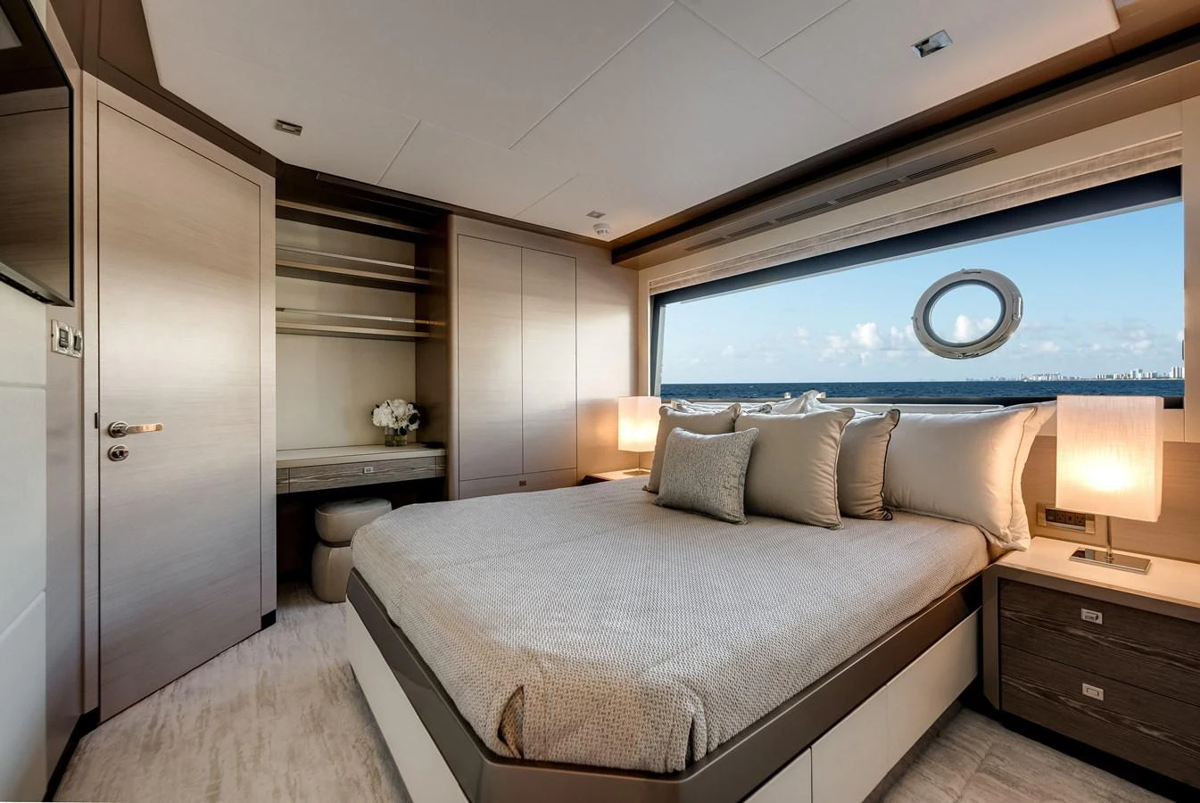 The stateroom features a luxurious bed with a scenic ocean view through a large window. aboard CHAOS Yacht for Sale