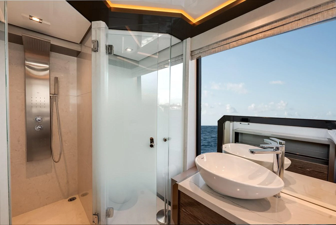 This luxurious bathroom features a modern shower and dual sinks with a stunning ocean view. aboard CHAOS Yacht for Sale