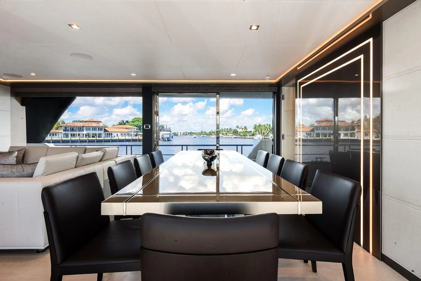 The yacht's dining area features a sleek table with comfortable seating and a stunning view of the water. aboard CHAOS Yacht for Sale