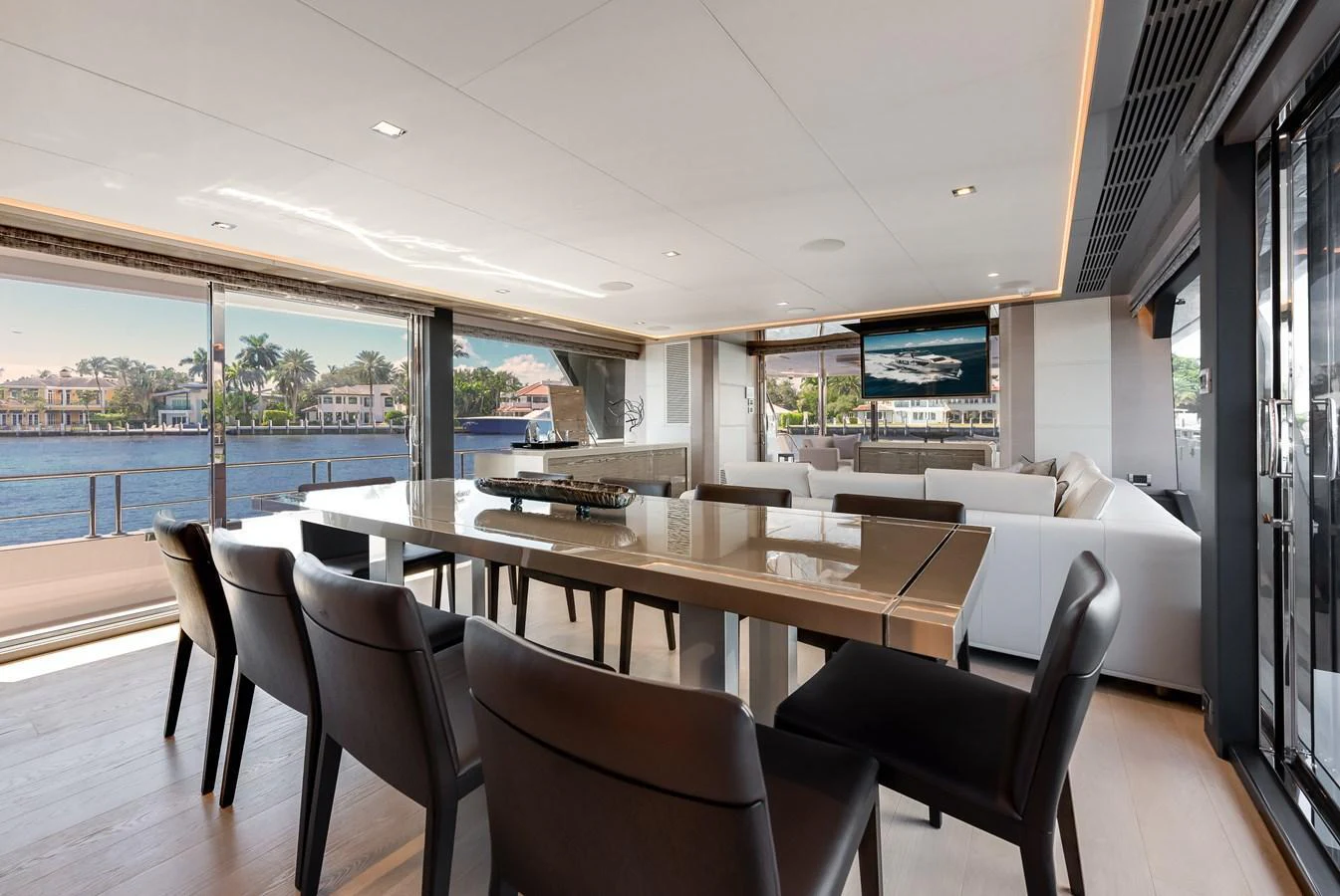 The spacious salon features modern furnishings and large windows offering stunning water views. aboard CHAOS Yacht for Sale