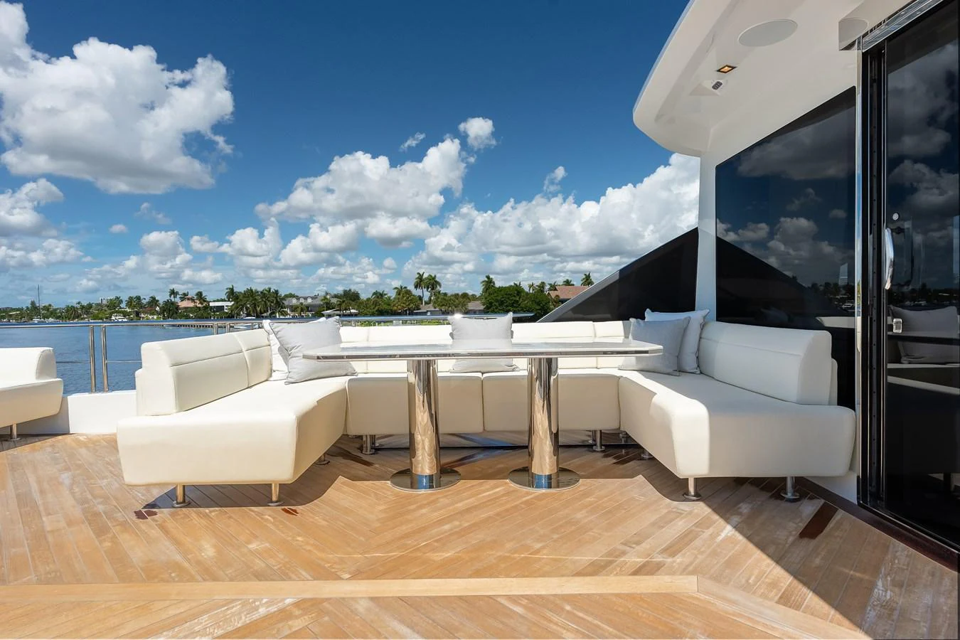 The aft deck features a stylish outdoor dining area with plush seating and a stunning view. aboard CHAOS Yacht for Sale