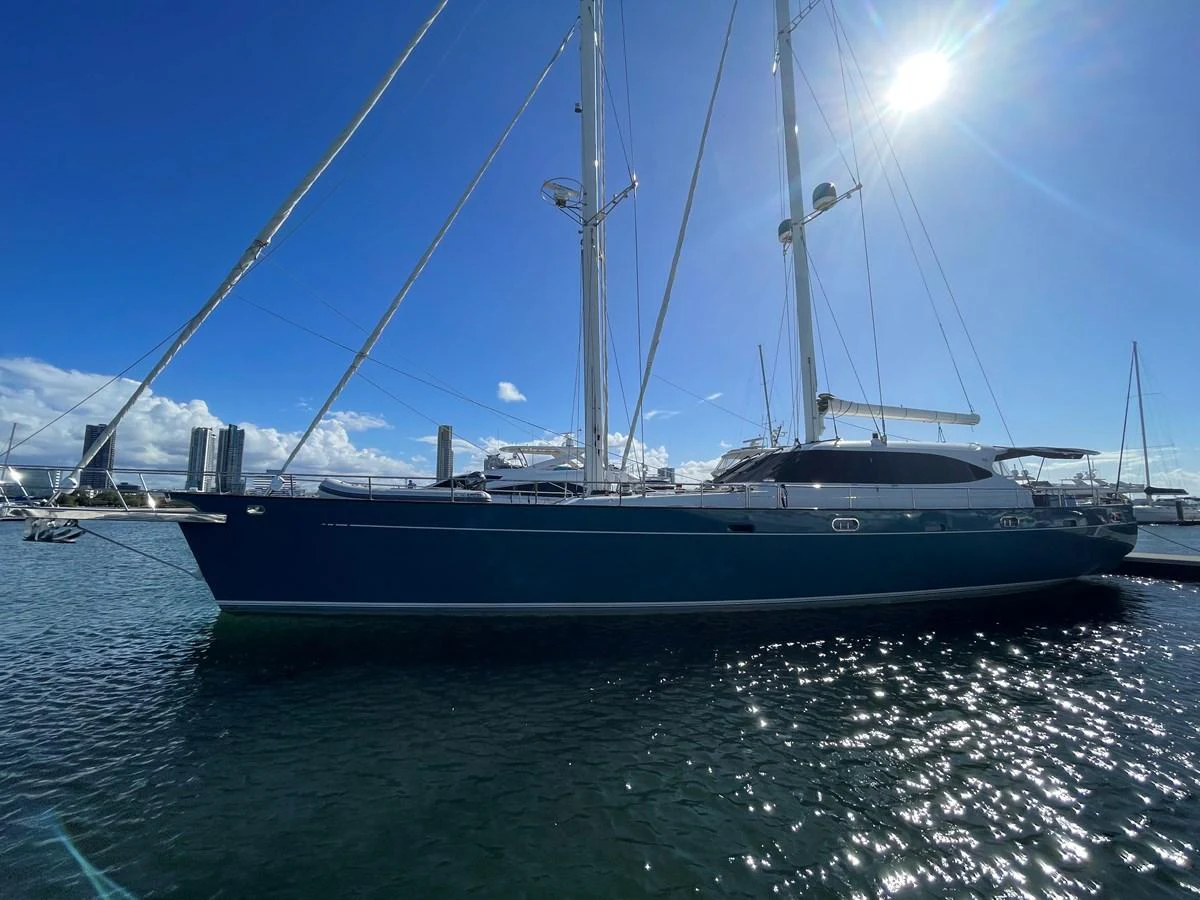 A sleek sailing yacht is docked under a clear blue sky, showcasing its elegant lines and tall masts. aboard SV TEAL Yacht for Sale