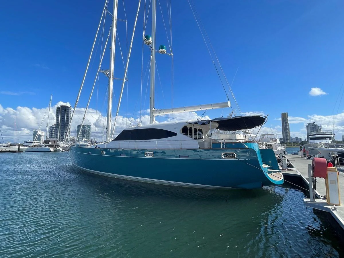 A sleek and modern yacht docked at a marina under a clear blue sky. aboard SV TEAL Yacht for Sale