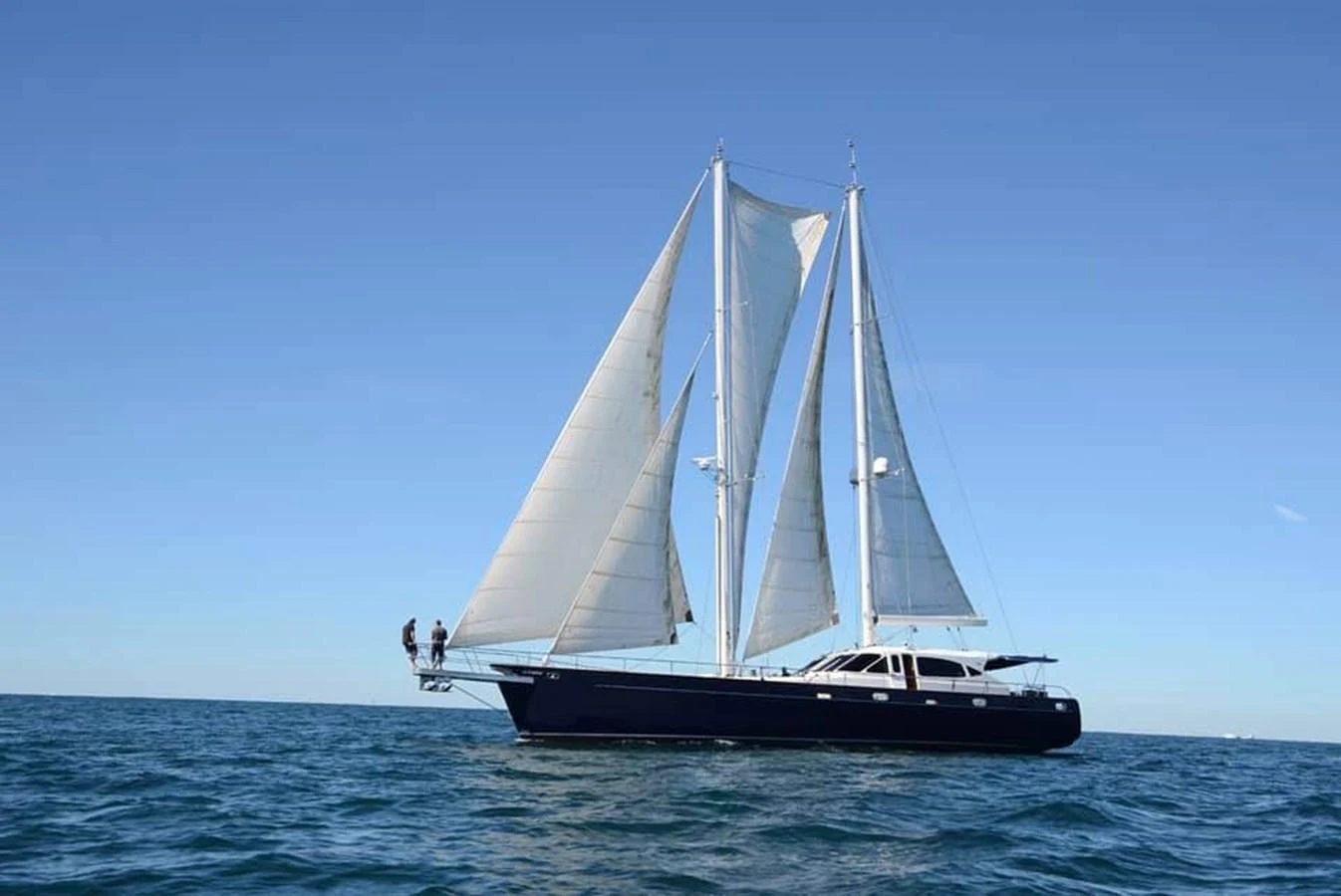 A sleek sailing yacht glides gracefully on the open sea under clear blue skies. aboard SV TEAL Yacht for Sale