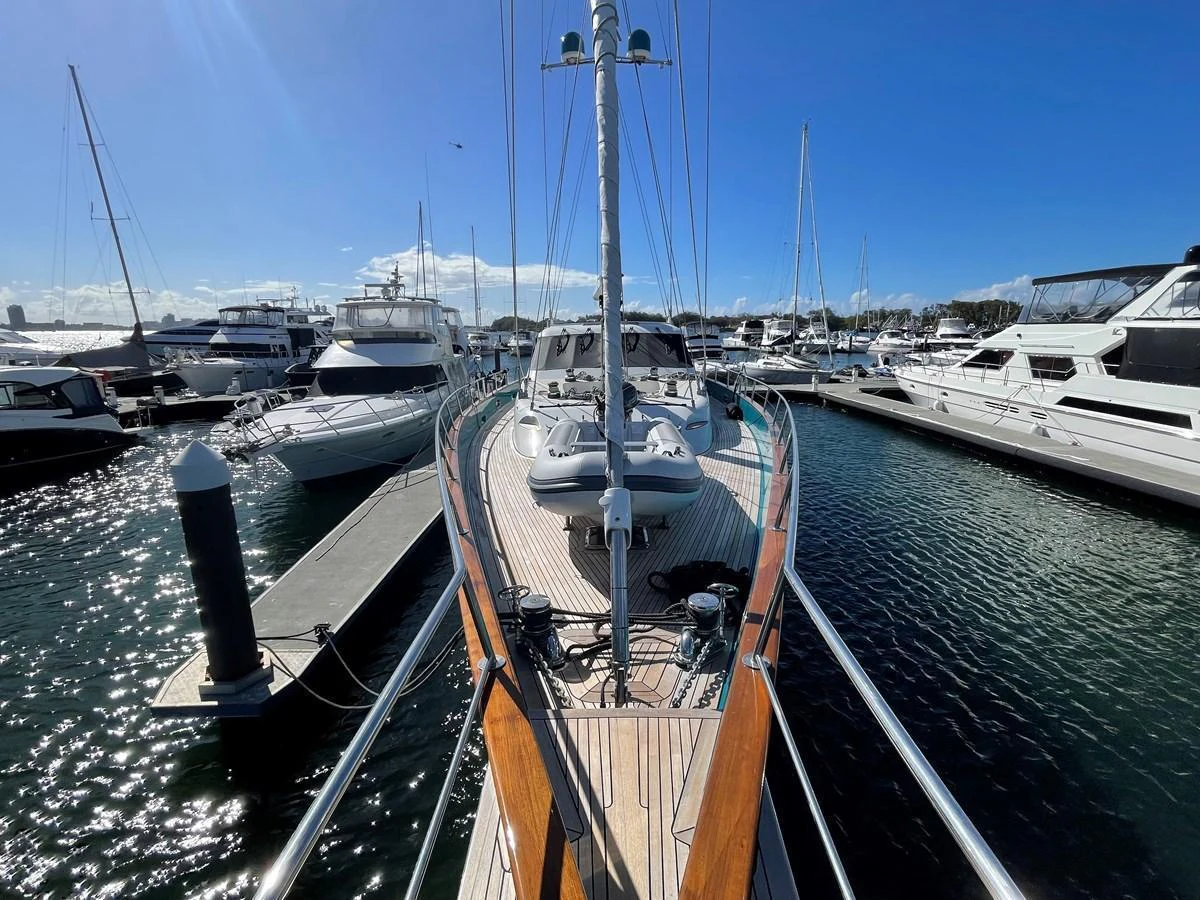 A sleek yacht is docked at a marina, showcasing its elegant deck and surrounding vessels. aboard SV TEAL Yacht for Sale